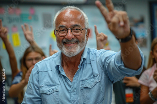 A senior male teacher with a joyful expression, making a peace sign with students raising hands in the background. Generative AI photo