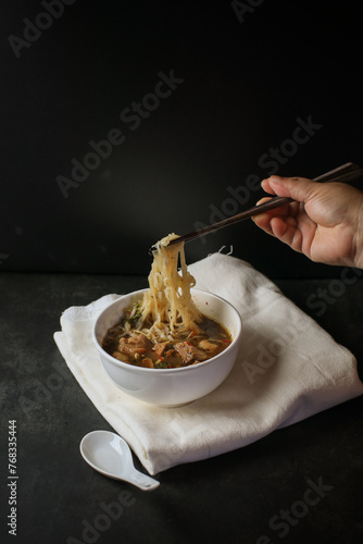 Thai Boat Noodle Soup. (Kuaytiaw Reua) Noodles with pork and pork balls with soup in white bowl. Asian food style. photo