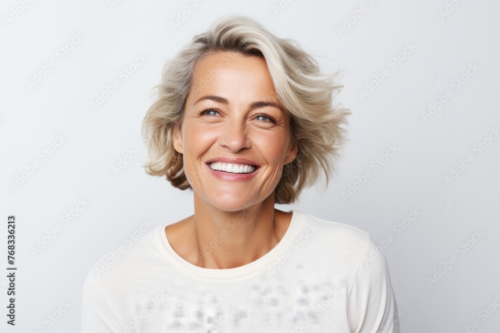 Portrait of happy smiling mature woman with blond hair over grey background Portrait of happy smiling mature woman with blond hair over grey background