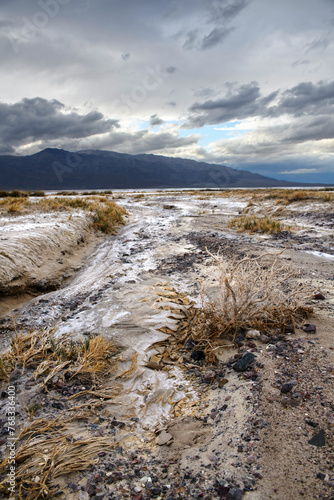 Death Valley riverbed with distant mountains uder a dramatic sky photo