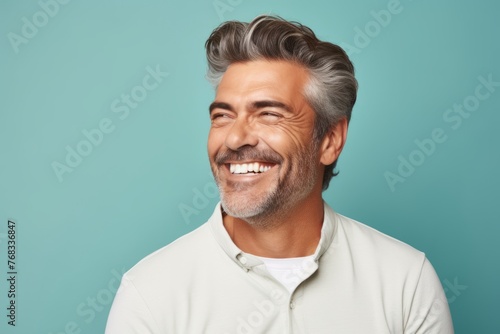 Handsome middle-aged man looking at camera and smiling while standing against blue background