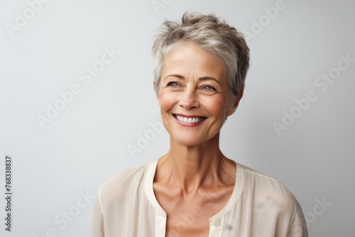 Portrait of happy senior woman looking at camera over grey background.