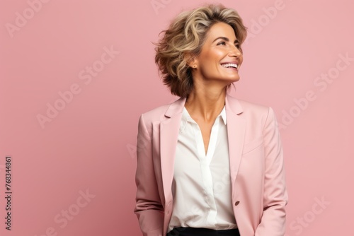 Portrait of smiling businesswoman in pink suit looking up over pink background