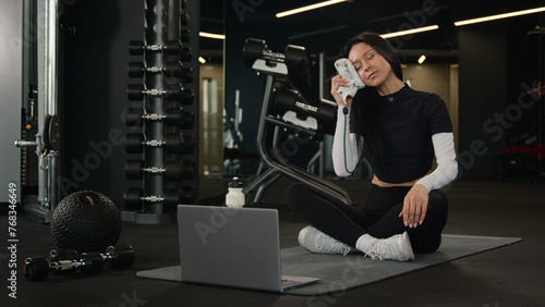 Female sport instructor trainer Caucasian woman wipe sweat with towel slim sportswoman girl teaching online workout on laptop fitness class in gym web training video tutorial yoga on digital device