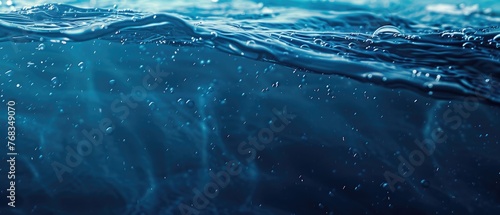 A serene image of deep dark blue water with gentle ripples and a scattering of tiny bubbles against a soft light gradient