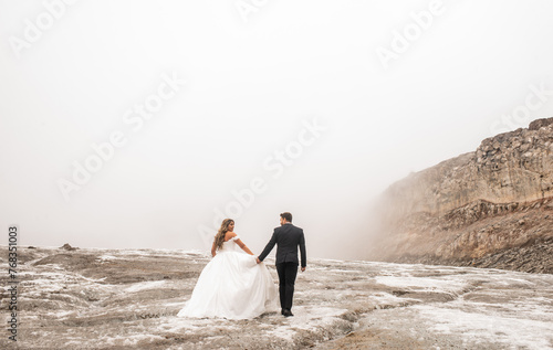 pareja de casados con sus vestidos de novios caminando en la montaña 