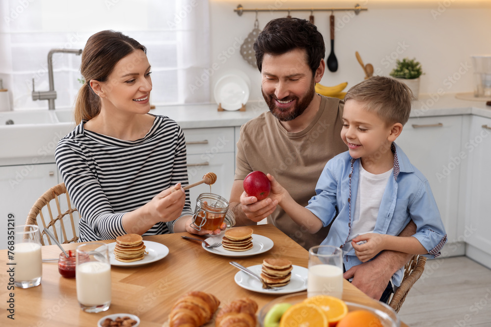 Happy family having breakfast at table in kitchen Happy family having breakfast at table in kitchen