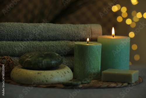 Spa composition. Burning candles, stones, soap and towels on grey table
