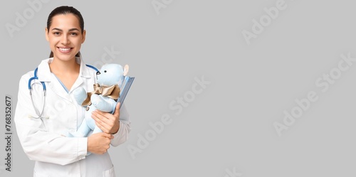 Portrait of female pediatrician on grey background with space for text