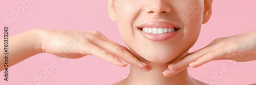 Young woman doing face building exercise on pink background, closeup