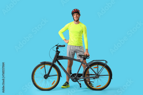 Fotografi Young male cyclist with bicycle on blue background