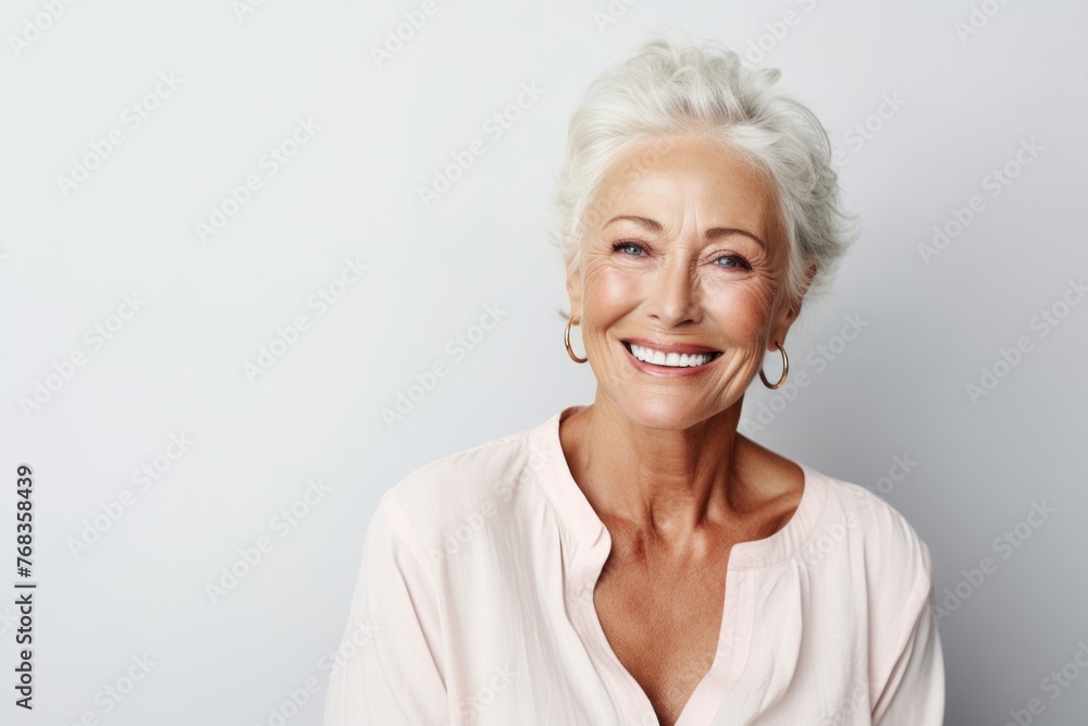 Portrait of a happy senior woman smiling at the camera against grey background
