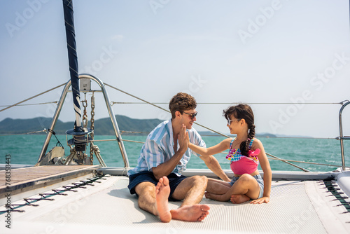Caucasian happy family sitting on deck of yacht while yachting outdoors.  © Kawee