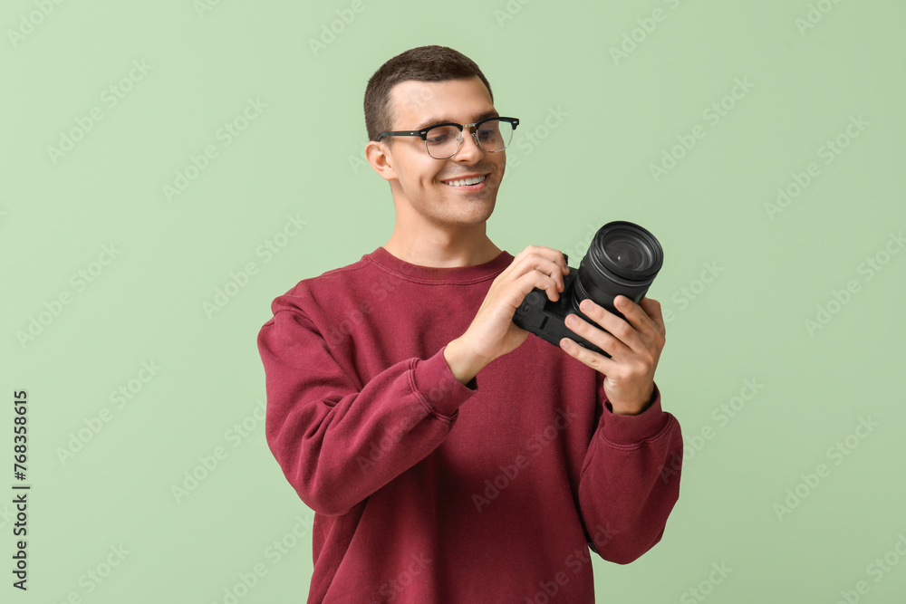 Naklejka premium Happy male photographer with modern camera on green background