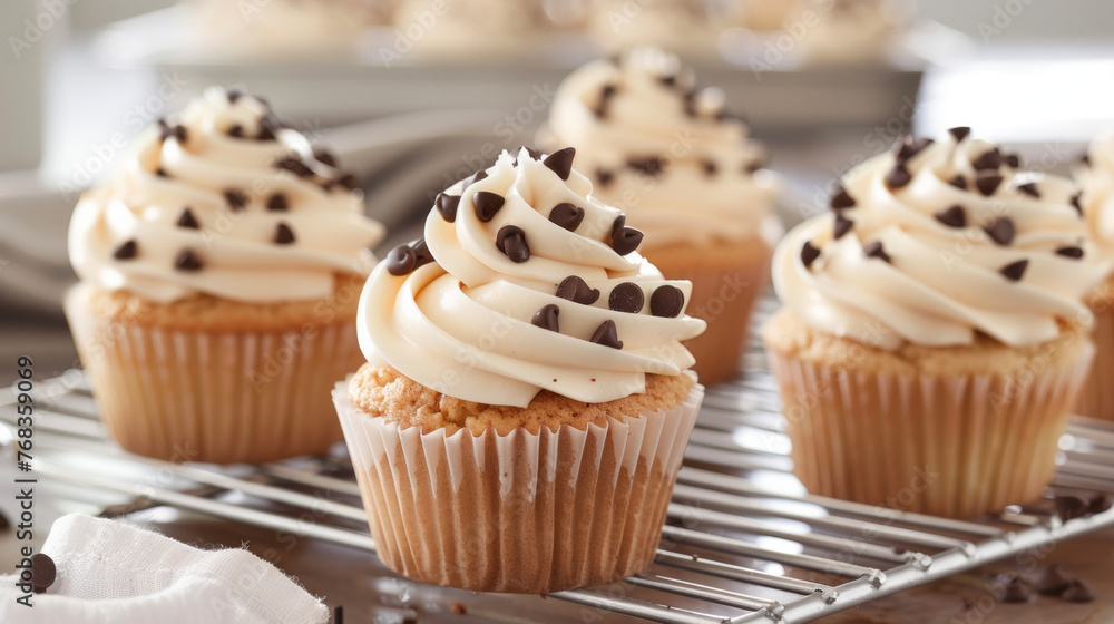 Cupcakes with white frosting and chocolate chips cooling on a rack. Cupcakes with white frosting and chocolate chips cooling on a rack.