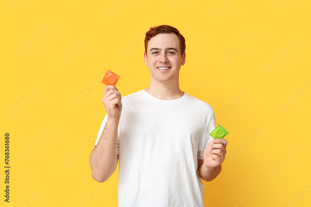 Young man with condoms on yellow background. Safe sex concept Young man with condoms on yellow background. Safe sex concept