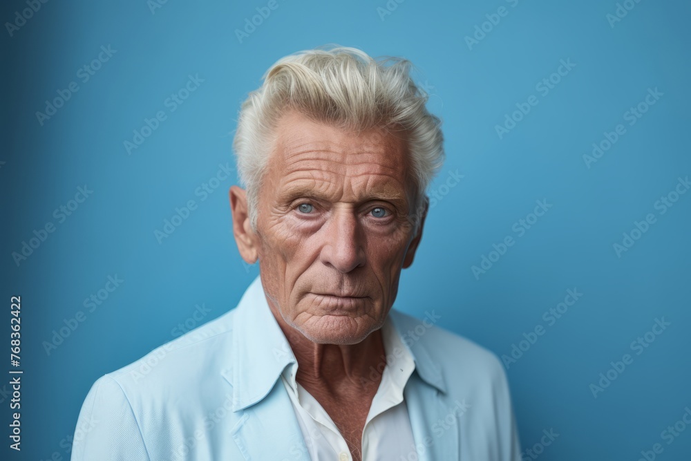 Portrait of a senior man looking at camera against blue background. Portrait of a senior man looking at camera against blue background.