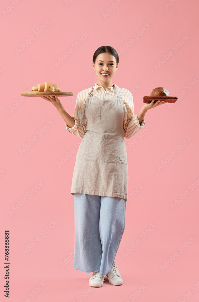 Female Asian baker with fresh pastry on pink background Female Asian baker with fresh pastry on pink background