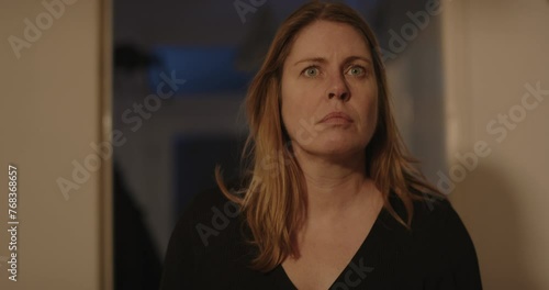 Frightened woman looking at something off screen, she gets scared and flees her home