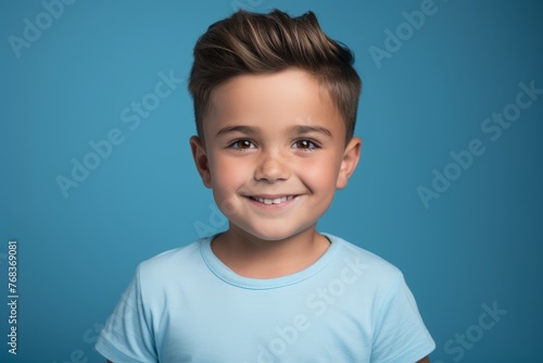 Portrait of a cute little boy smiling and looking at camera against blue background