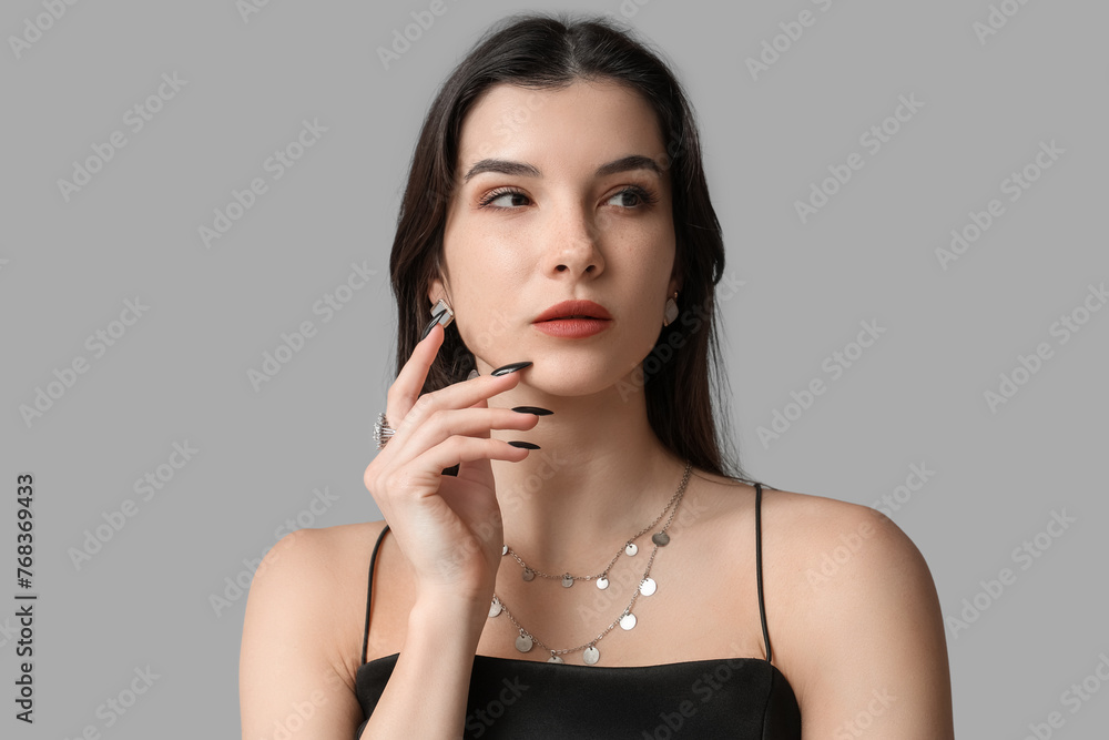 Obraz premium Beautiful young woman with stylish jewelry on grey background