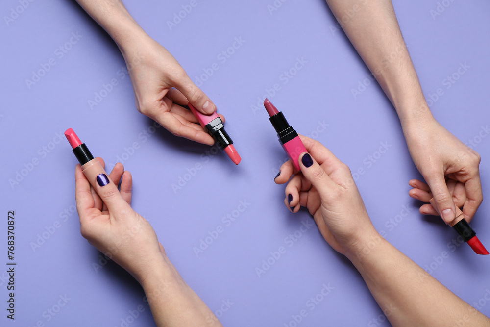 Female hands with lipsticks on purple background Female hands with lipsticks on purple background