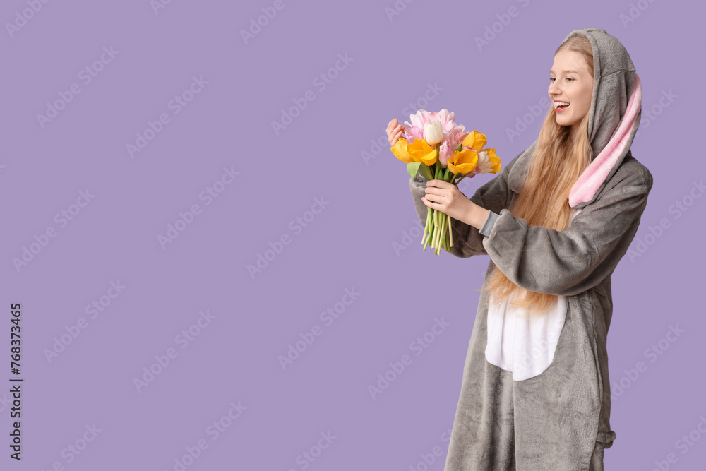 Beautiful young happy woman in bunny costume with bouquet of flowers on purple background. Easter celebration Beautiful young happy woman in bunny costume with bouquet of flowers on purple background. Easter celebration
