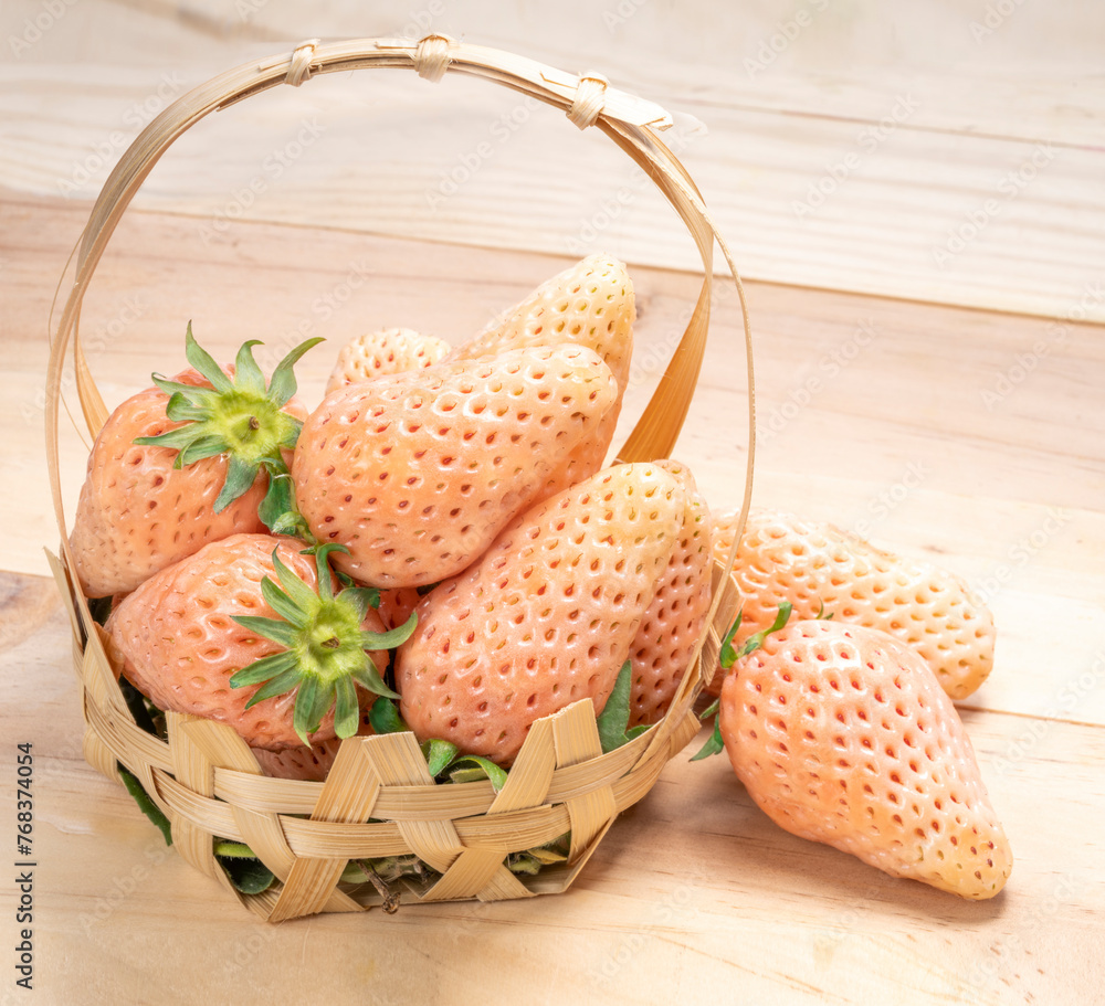 Pink snow strawberry in bamboo basket on wooden background, White and Pink snow Strawberries on wooden table.