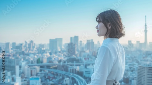 A beautiful Asian woman wearing a white shirt smiling while looking at the cityscape.