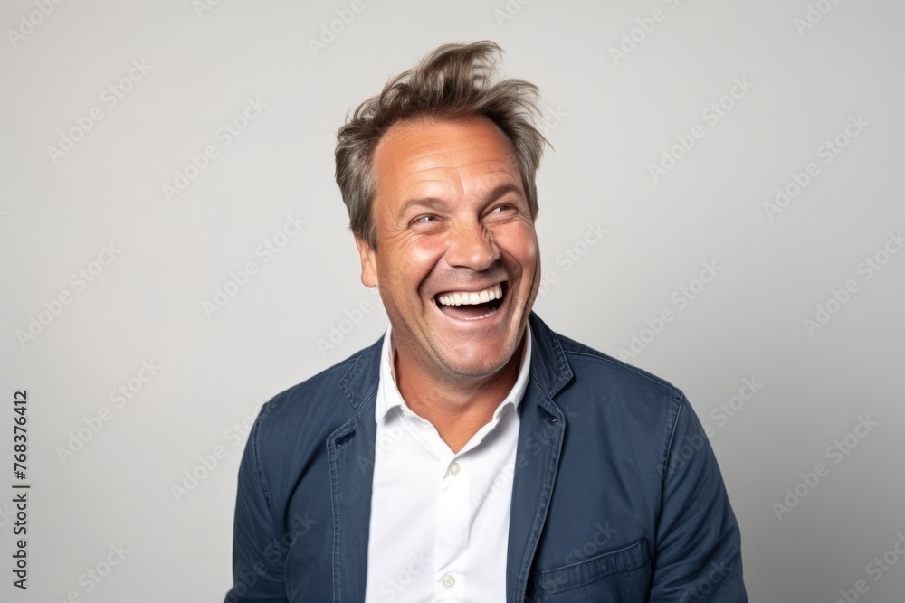 Portrait of a happy senior man laughing against a grey background.
