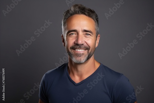 Portrait of a handsome middle-aged man smiling at the camera on a dark background