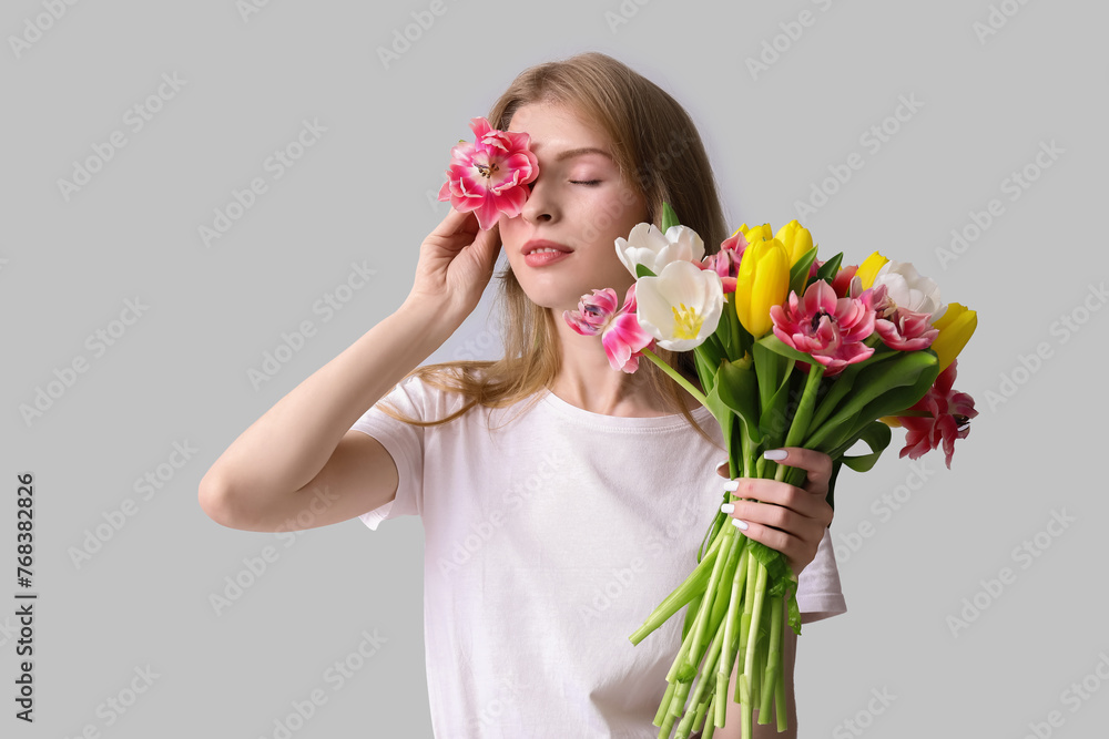 Pretty young woman with bouquet of beautiful tulips on grey background Pretty young woman with bouquet of beautiful tulips on grey background