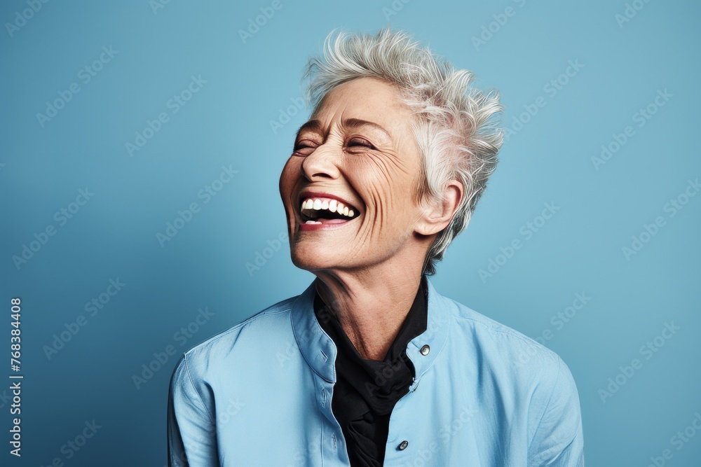 Portrait of an attractive senior woman laughing against a blue background. Portrait of an attractive senior woman laughing against a blue background.