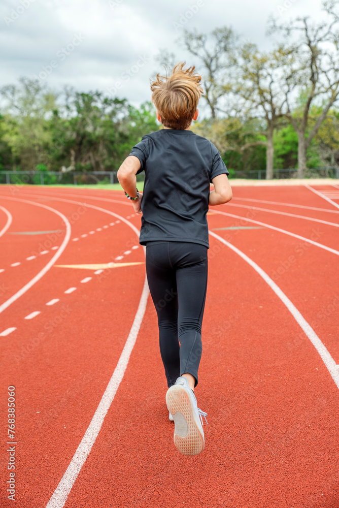 Fototapeta premium Youth male track team runner in first place running in a race 