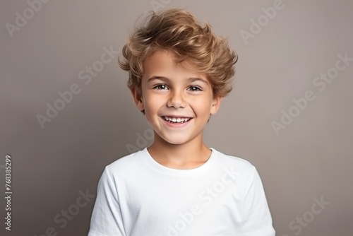 Portrait of a smiling little boy with blond curly hair over gray background © Chacmool