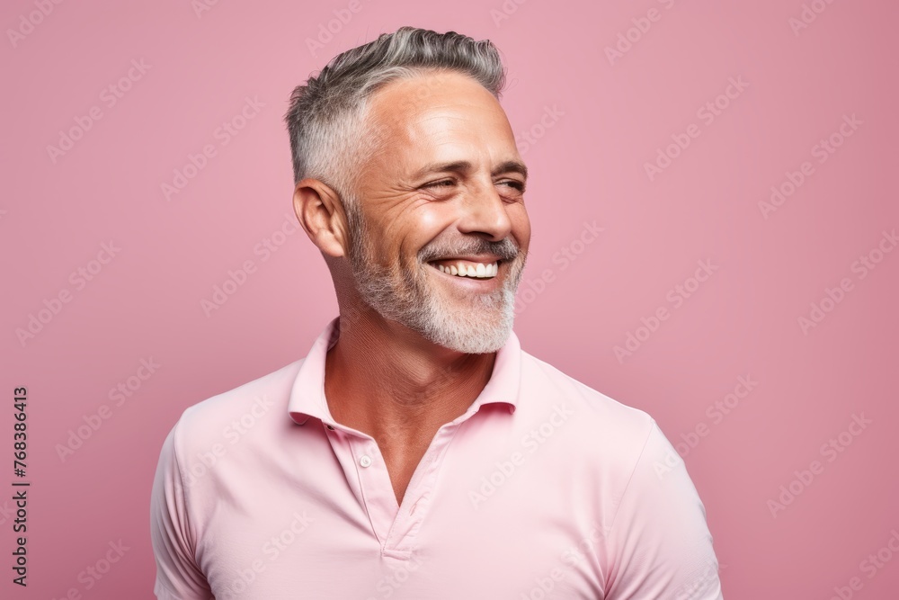 Cheerful senior man looking at camera and smiling while standing against pink background Cheerful senior man looking at camera and smiling while standing against pink background