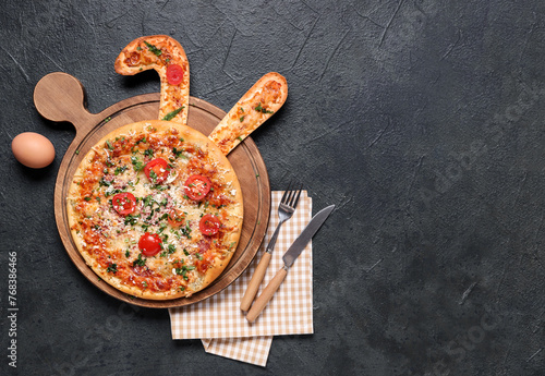 Tasty Easter pizza with bunny ears, egg and cutlery on black background © Pixel-Shot