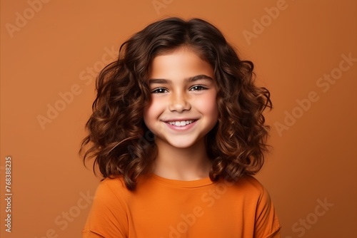 Portrait of a cute little girl with curly hair over brown background