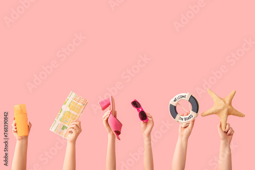 Female hands with starfish, sunglasses, sunscreen, map,  decorative lifebuoy and heeled sandal on pink background. Travel concept.