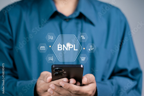 BNPL or Buy Now Pay Later concept, Businessman using smartphone with BNPL icon on virtual screen.