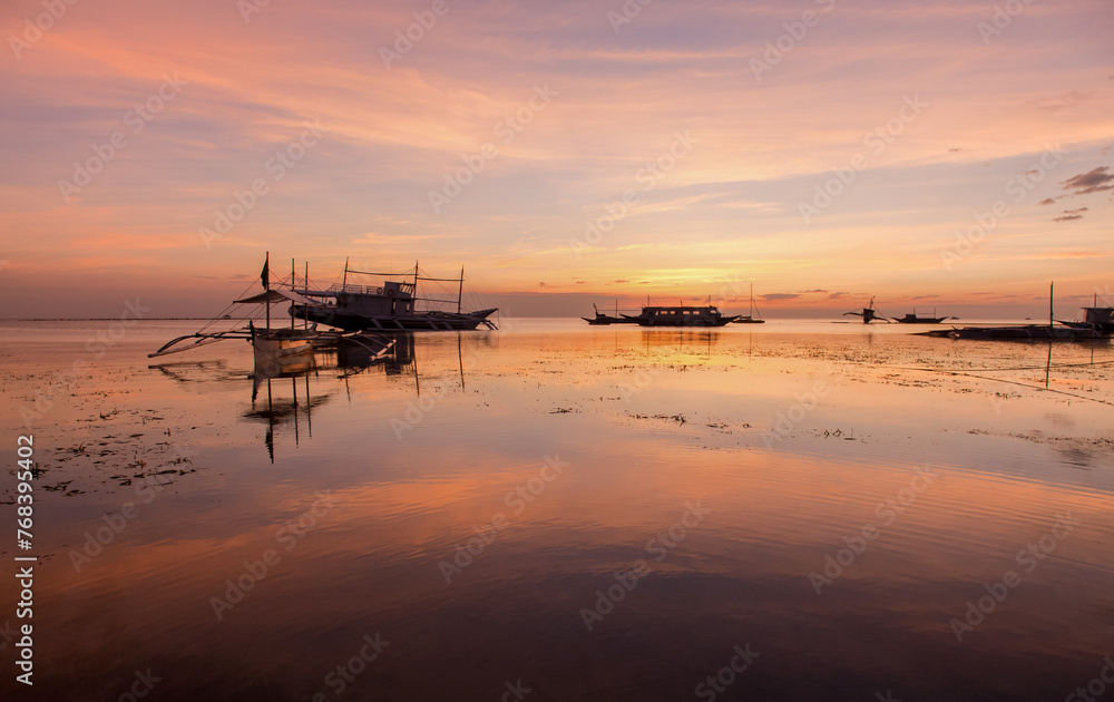 Golden Sunset Serenity with reflection. A tranquil beach scene at dusk with boats silhouetted against the horizon. Nature’s beauty in perfect harmony.