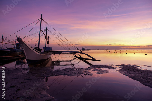 Golden Sunset Serenity. A tranquil beach scene at dusk with boats silhouetted against the horizon. Nature’s beauty in perfect harmony. photo