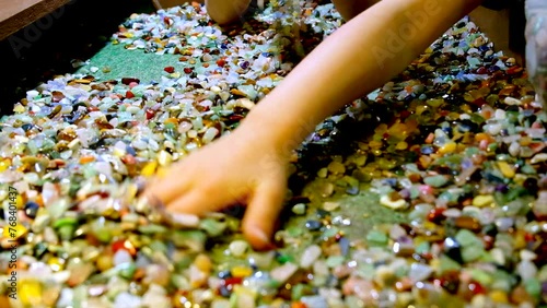 Kids rummage through wide selection of colorful gemstones with their hands photo