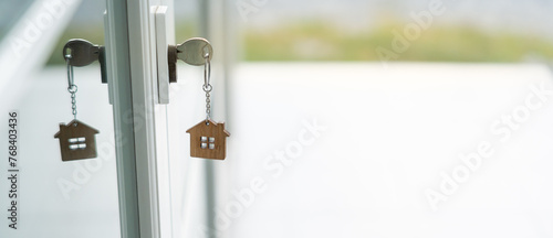 Landlord key for unlocking house is plugged into the door. Second hand house for rent and sale. keychain is blowing in the wind. mortgage for new home, buy, sell, renovate, investment, owner, estate photo