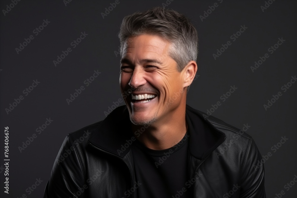 Portrait of a happy mature man laughing against a dark background. Portrait of a happy mature man laughing against a dark background.