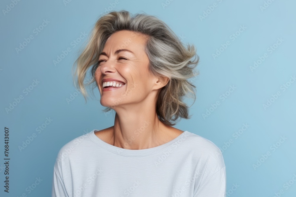 Portrait of a happy middle-aged woman laughing against blue background Portrait of a happy middle-aged woman laughing against blue background