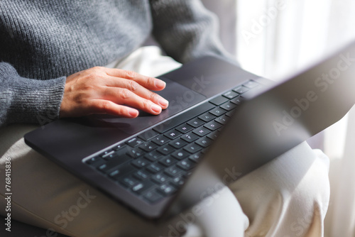 Closeup image of a woman working and touching on laptop computer touchpad at home