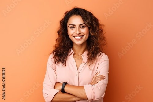 Portrait of a happy young businesswoman standing with arms crossed over orange background