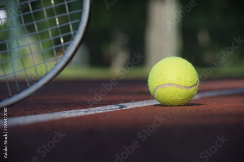 Tennis racquet and yellow tennis ball near white line © NetPix