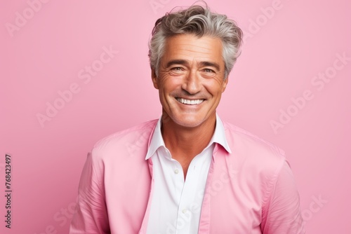 Portrait of a happy senior man smiling at camera over pink background